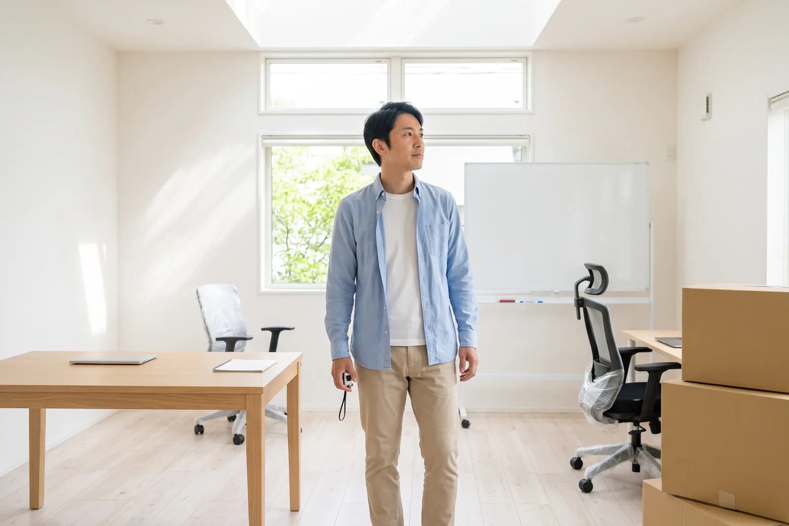 開業準備中の事務所で、独立を考える不動産会社員が、新しい机の配置を確かめるように室内を見渡している様子