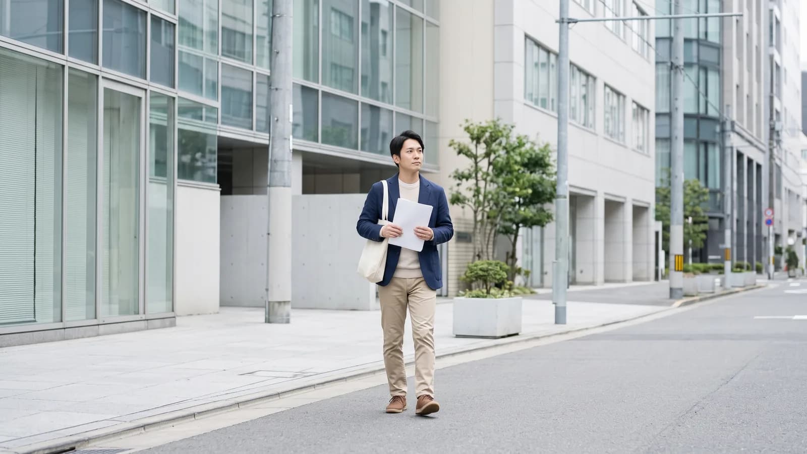 開業を控えた会社員大家が、手続きのためにビジネス街の歩道を歩いている様子
