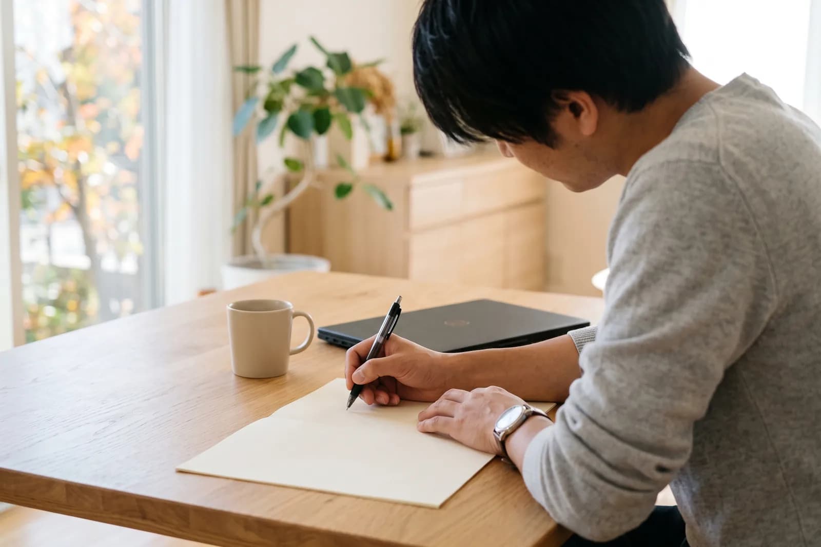 開業を考える人が、机の上で紙にペンを走らせて資金計画を練っている手元