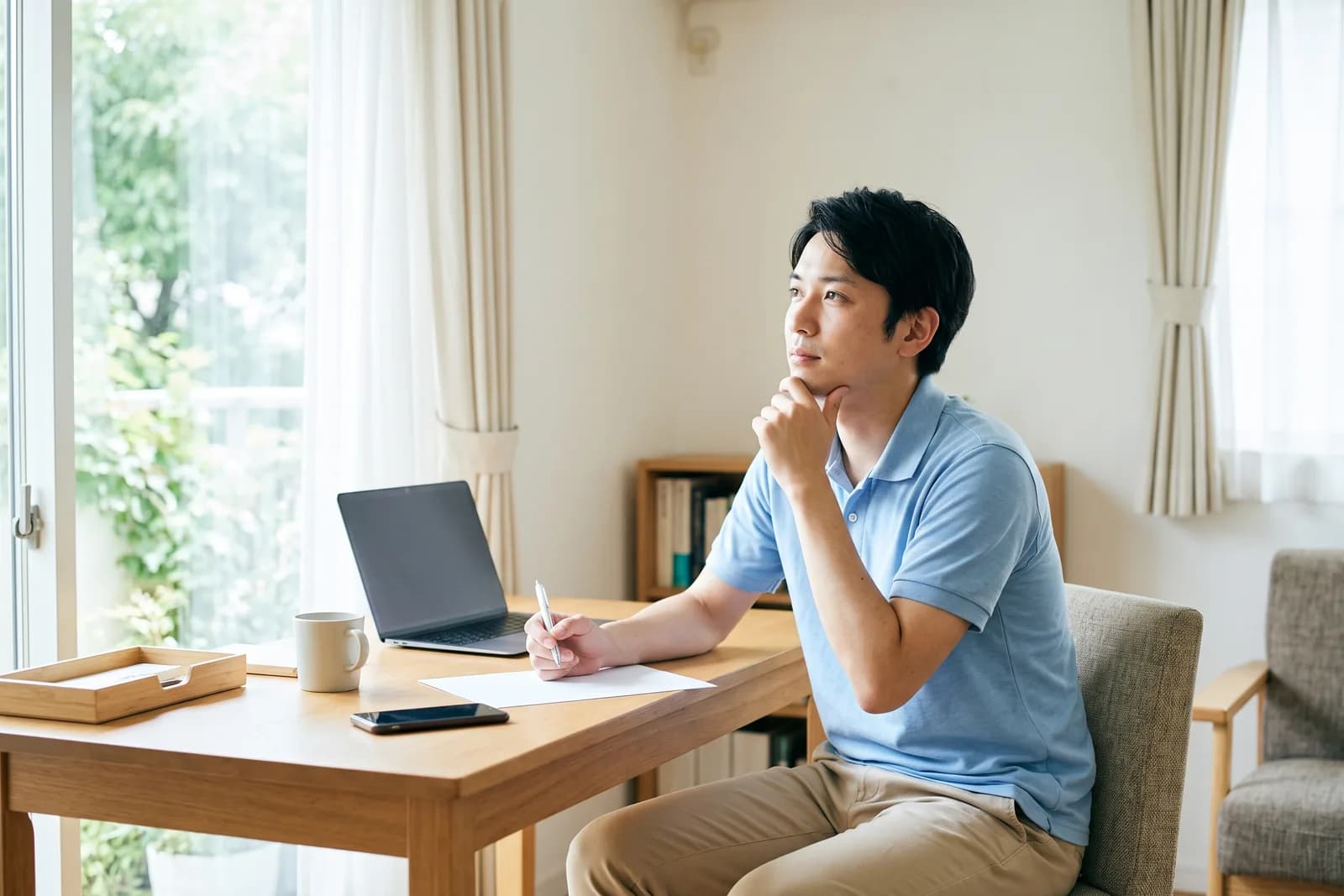 宅建に合格した会社員が、自宅の机で考え事をしている様子